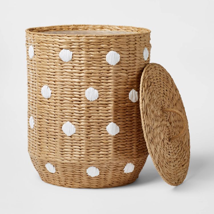 A woven hamper with a lid, featuring a natural colored base and white colored polka dots.