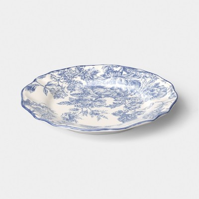 A white colored plate with blue floral patterns and a scalloped edge.