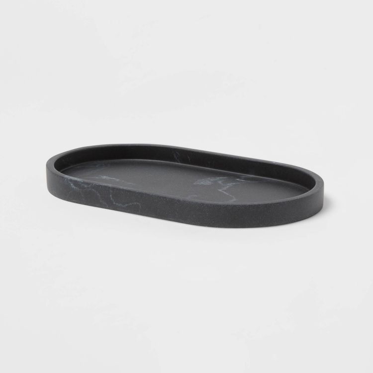 A black colored oval tray with a slightly raised edge and subtle marbling pattern.
