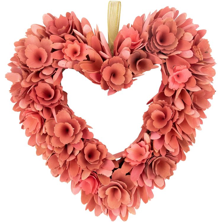 Heart-shaped wreath made of pink colored paper flowers with a gold colored ribbon for hanging.