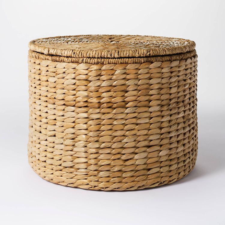 A round, woven, natural colored ottoman with a textured surface.