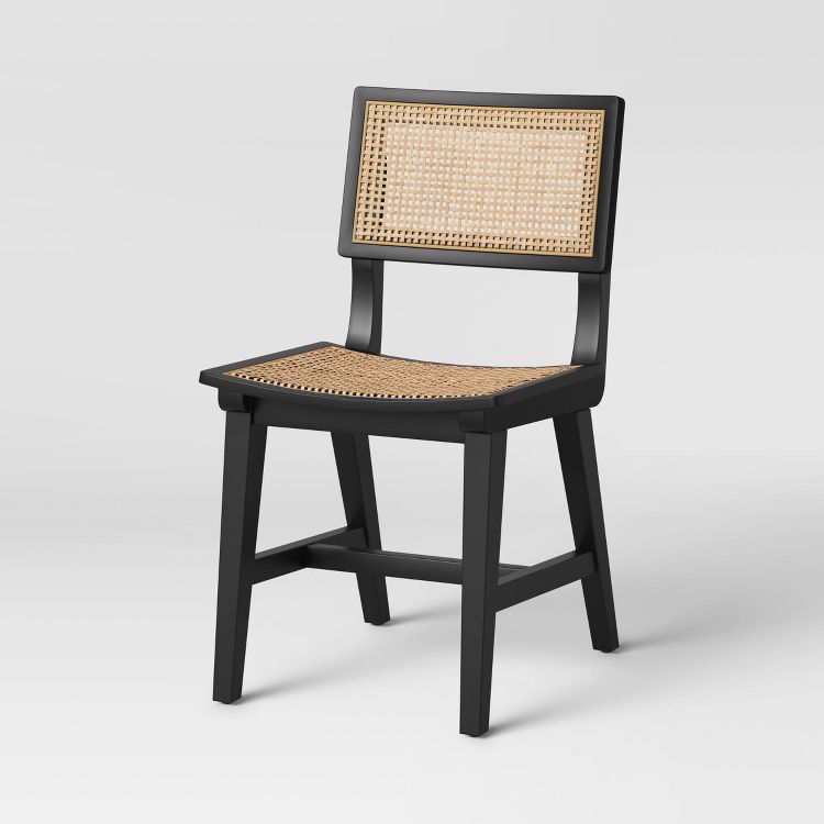 A black colored dining chair with a woven rattan seat and backrest.