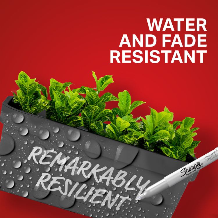 A white marker labeled "Sharpie Permanent Marker" writes "REMARKABLY RESILIENT" on a black surface with water droplets, against a red background with the text "WATER AND FADE RESISTANT" and green plants in the background.