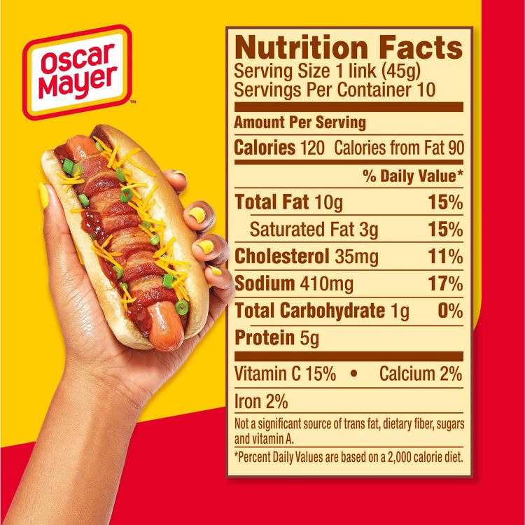 A hand holding a hot dog topped with bacon, shredded cheese, and green onions next to a nutrition facts label showing details like 120 calories per serving.