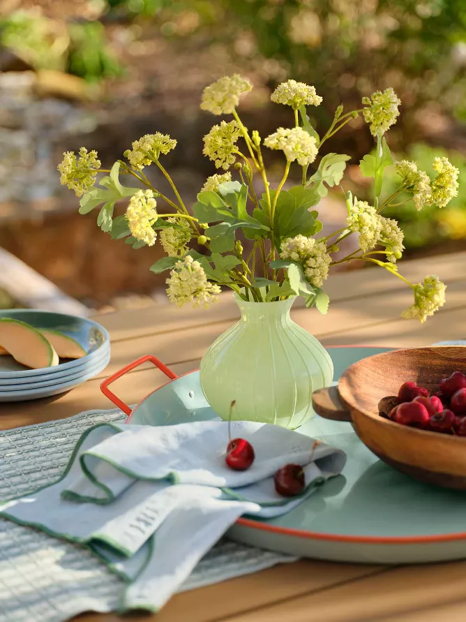 Faux greenery in pale green vase on outdoor tray