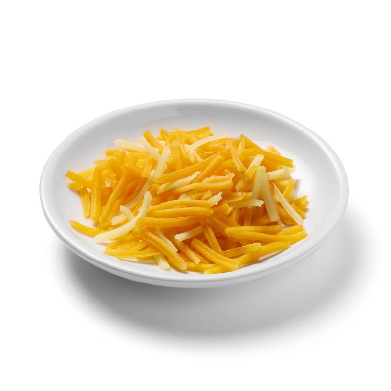 Shredded yellow and white colored cheese on a white plate.