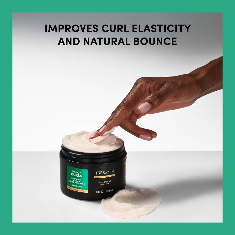 A hand dipping into a black jar of TRESemmé Bouncy Curls Multi-Tasking Hair Mask with cream-colored product, labeled 8 fl oz / 236 ml, against a background with text "IMPROVES CURL ELASTICITY AND NATURAL BOUNCE."