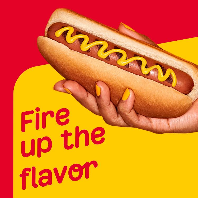 A hand holding a hot dog with mustard on a bun, next to the text "Fire up the flavor" in red on a yellow and red background.