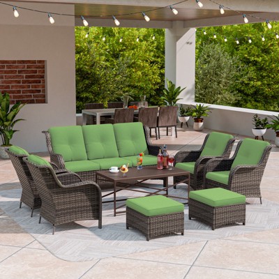 Outdoor patio seating arrangement with sofa, chairs, and ottomans with green cushions