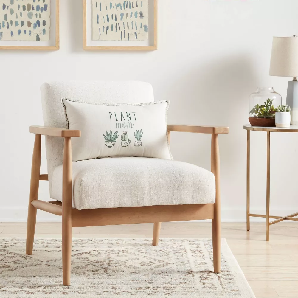 green and white lumbar pillow on a cream colored chair. 