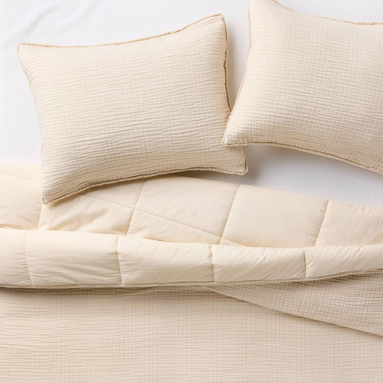 Natural-colored textured chambray comforter and sham set on a bed, featuring a subtle grid pattern.