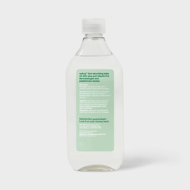 Clear plastic bottle with a white cap containing fast-absorbing baby oil, featuring a green label with product information.