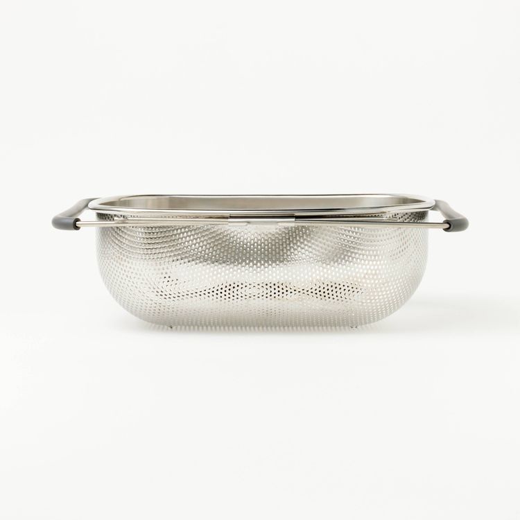 A silver colored colander with black handles and a perforated design.