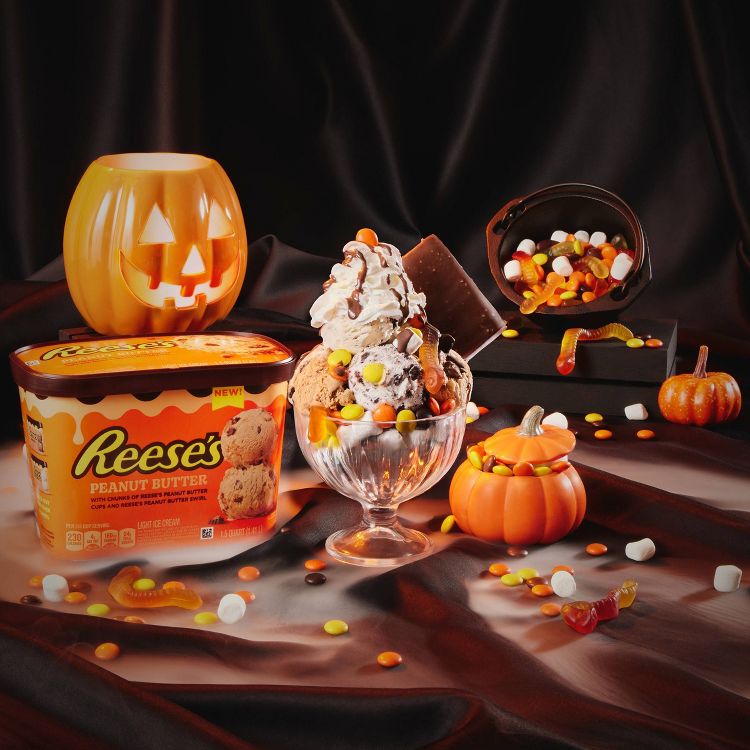 A festive Halloween-themed display showcases various ice cream brands, including Breyers Cookies & Cream, Talenti Gelato Layers, Ben & Jerry's Chocolate Chip Cookie Dough, Klondike Heath, and Reese's Peanut Butter. 