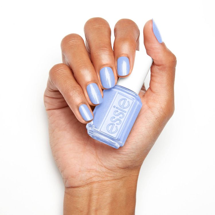 A hand holding a bottle of light blue colored nail polish with matching polish applied on the nails.