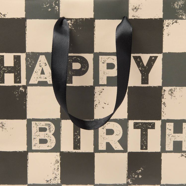 A checkered gift bag with black and beige colored squares and the text "HAPPY BIRTH" partially visible, featuring a black colored handle.