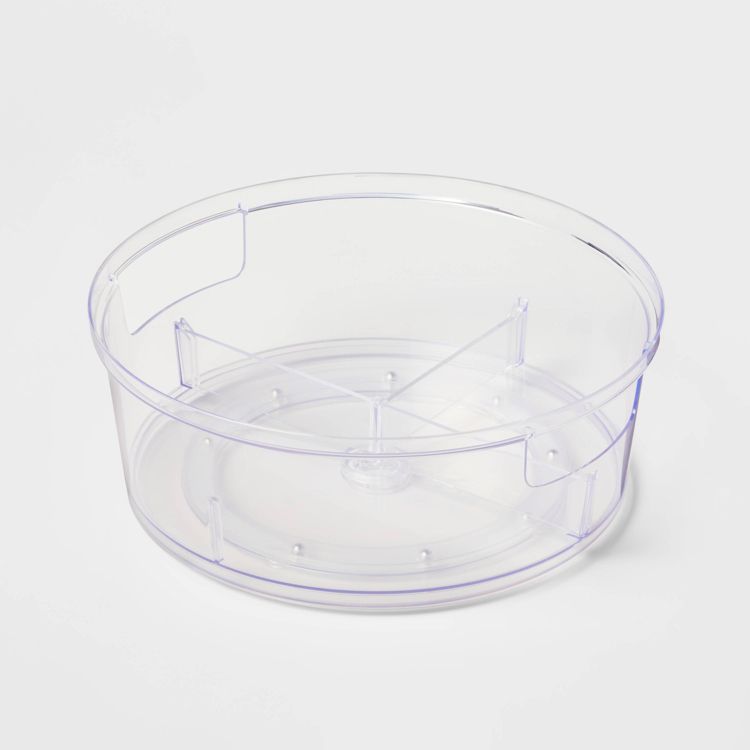 A clear round plastic container with internal dividers for kitchen storage.