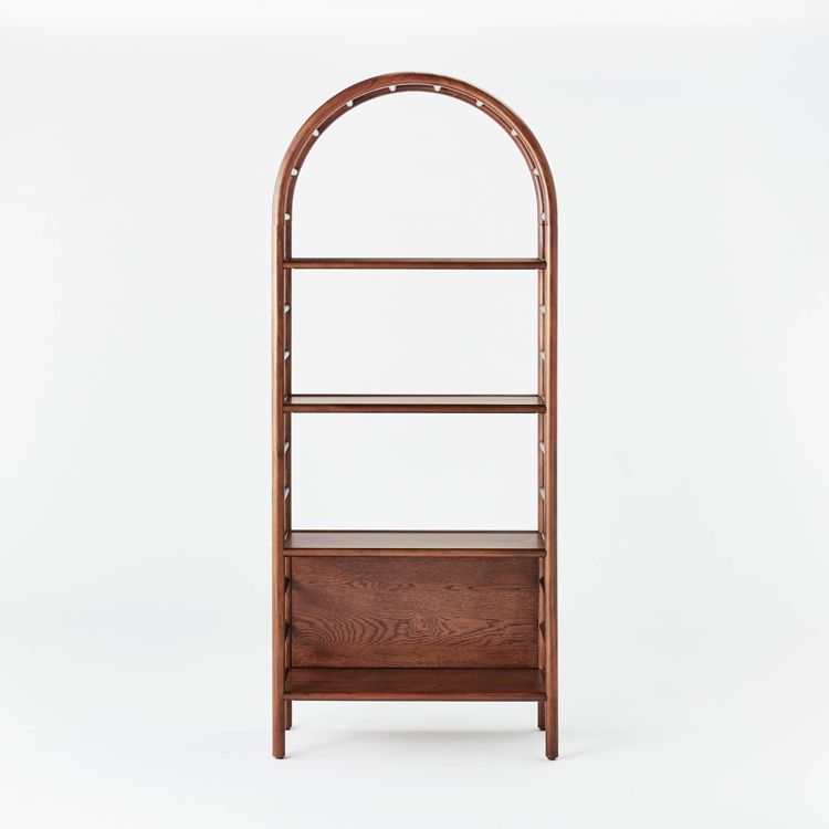 A brown colored arched bookcase with three shelves and a closed compartment at the bottom.