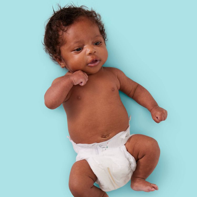 A baby wearing a white colored diaper lying on a light blue background.