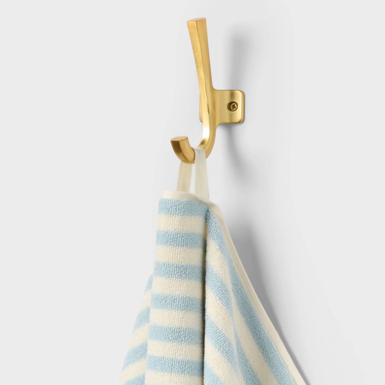 A blue and white striped towel hanging on a gold colored wall hook.