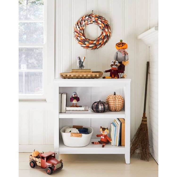 White decorative coiled rope basket on a shelf, surrounded by books and plush toys.