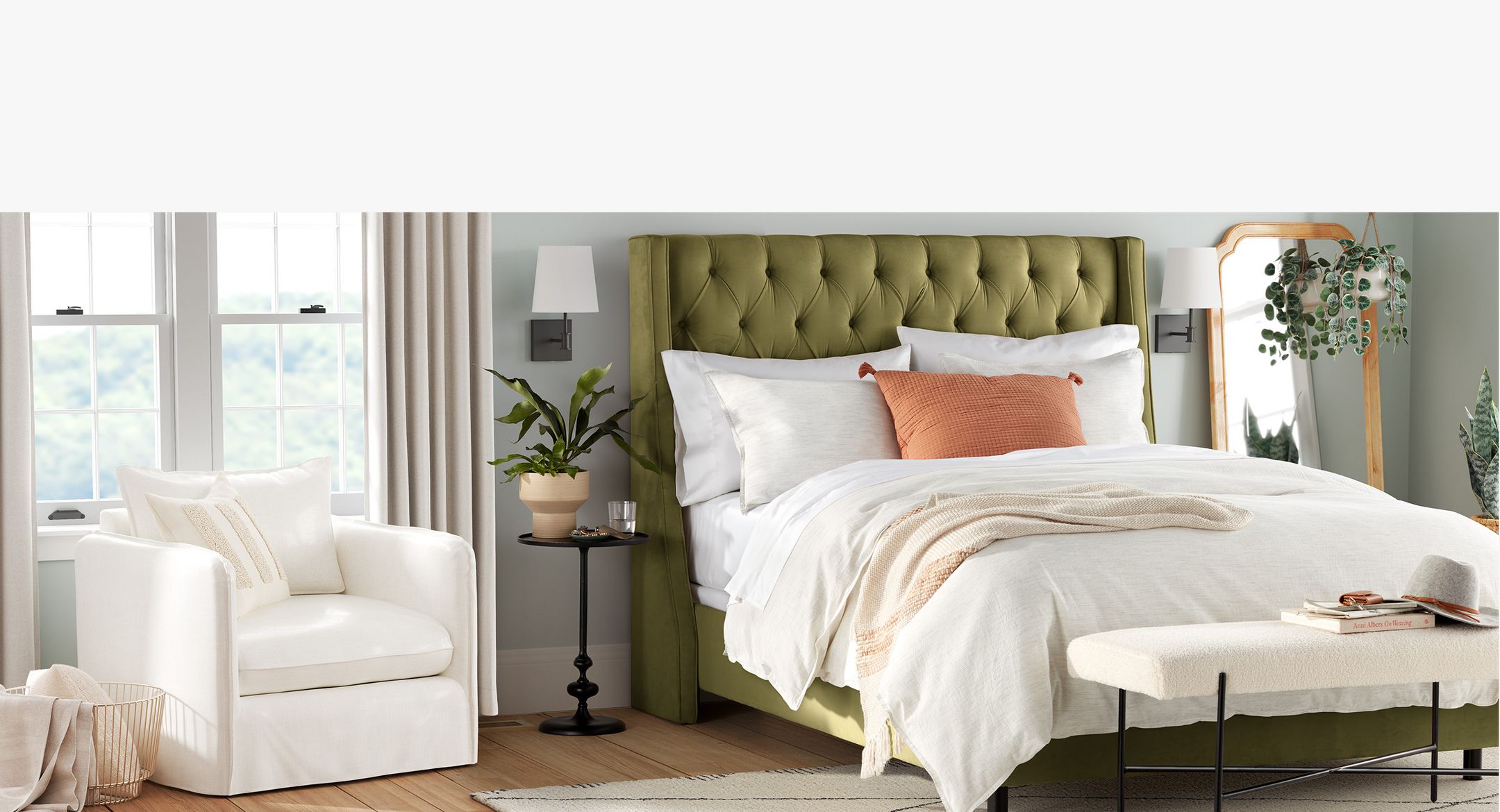 Bedroom with made-to-order white chair on the left and Bed with green cushion head board on the right. 