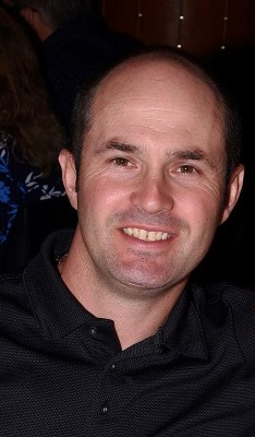 Headshot of Adam, a man with pale skin, brown eyes, wearing a polo shirt