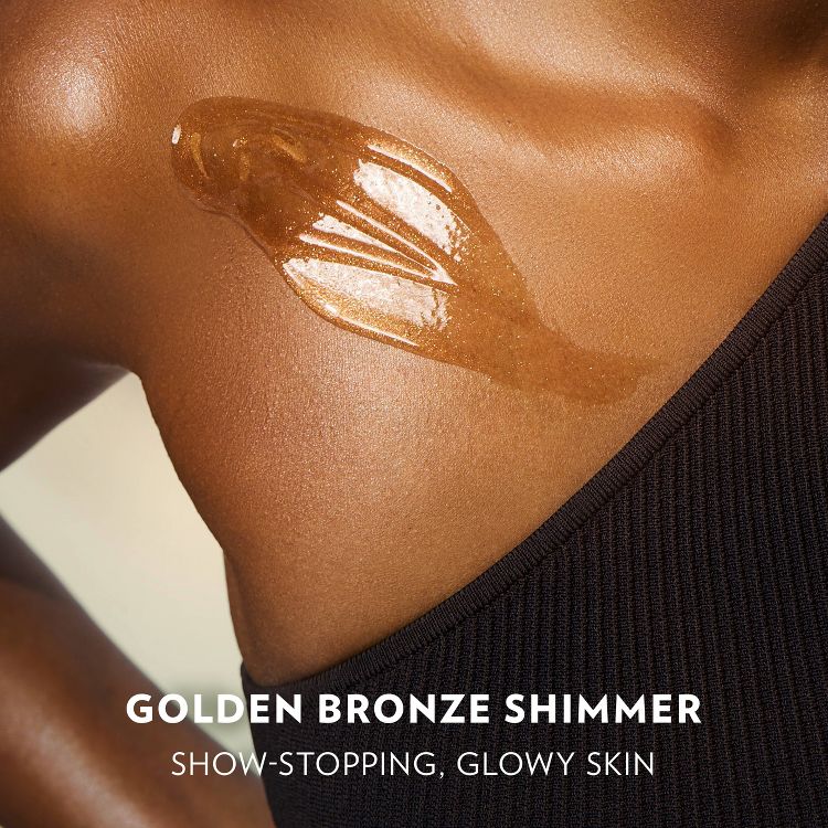 Golden Bronze Shimmer on a woman's radiant skin, showcasing show-stopping, glowy skin. The shimmer highlights her medium skin tone beautifully.