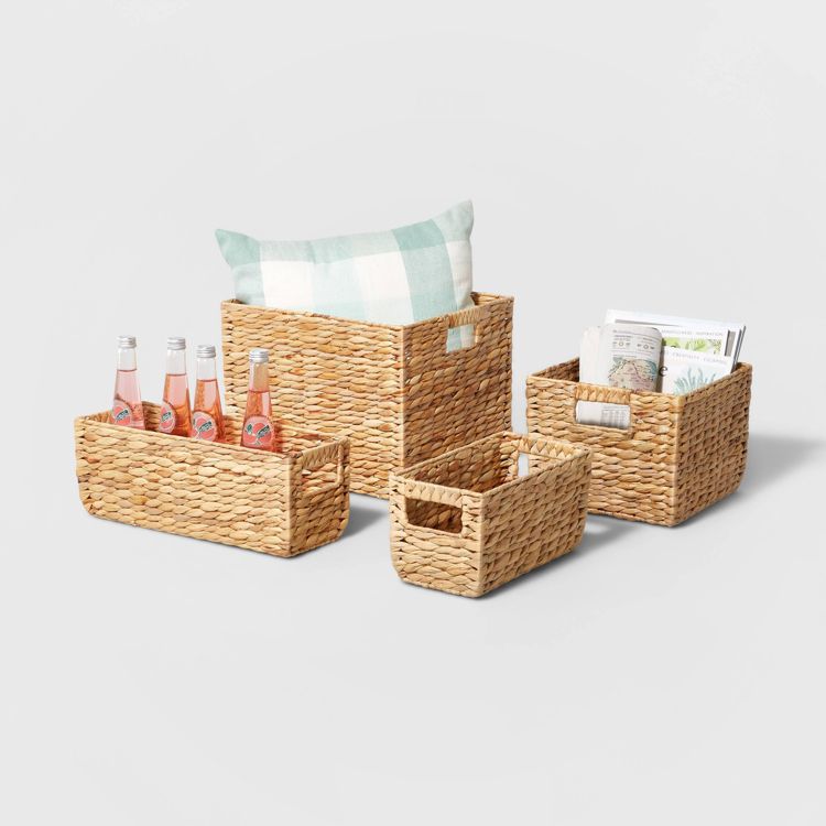 Four woven baskets of varying sizes, one holding a pillow, another with bottles, and a third containing magazines.