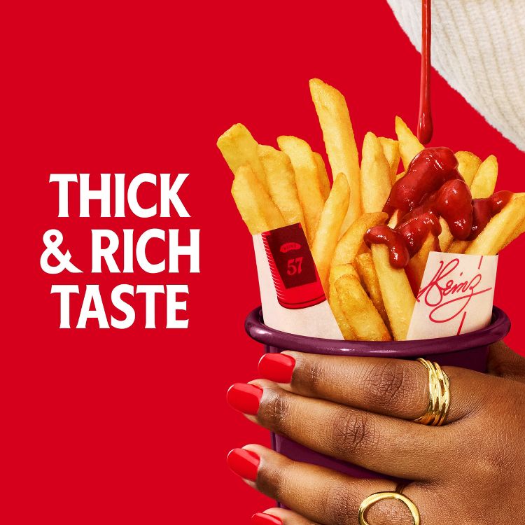 Red colored ketchup being poured over golden colored fries held by a hand, with white text reading "THICK & RICH TASTE" and a visible Heinz signature on the fry wrapper.
