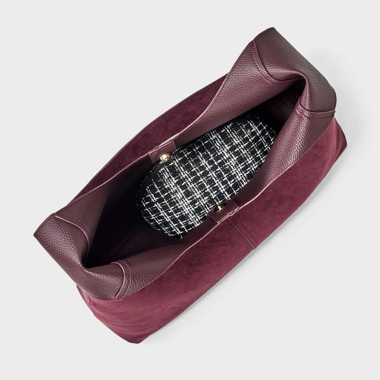 A burgundy colored bag with a black and white patterned interior.