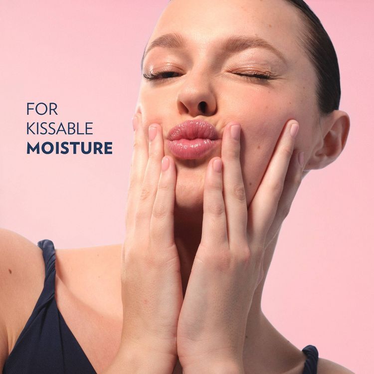 A person with glossy lips puckering and holding their cheeks, with the text "FOR KISSABLE MOISTURE" on a pink background.