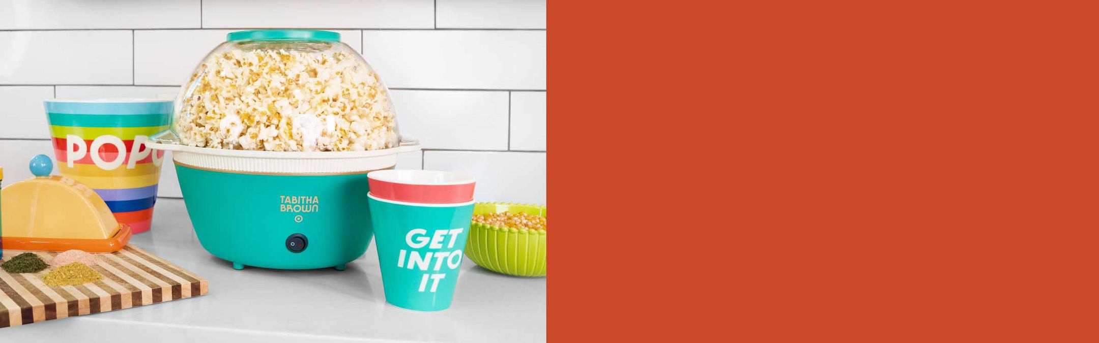 A popcorn maker on the counter full of fresh popcorn, surrounded by other accessories from Tabitha Brown's new kitchen collection.