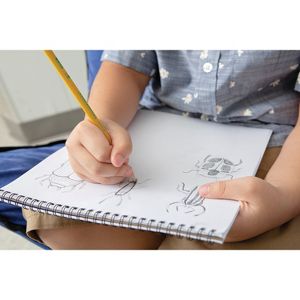 A hand holding a yellow colored pencil sketching insects on a spiral-bound notebook.