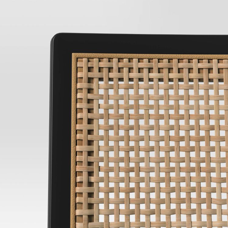 A close-up of a dining chair backrest with a woven pattern in light brown colored material framed by a black border.
