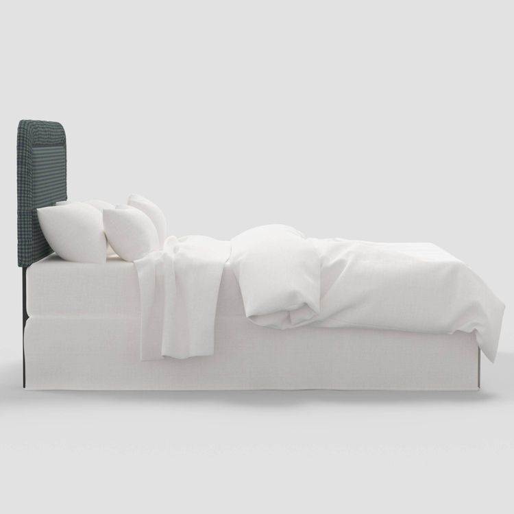 A bed with a dark colored textured headboard and white bedding, including pillows and a duvet.
