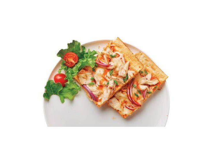 Two rectangular slices of pizza topped with chicken, red onion, and herbs on a white plate with a side of lettuce and cherry tomatoes.