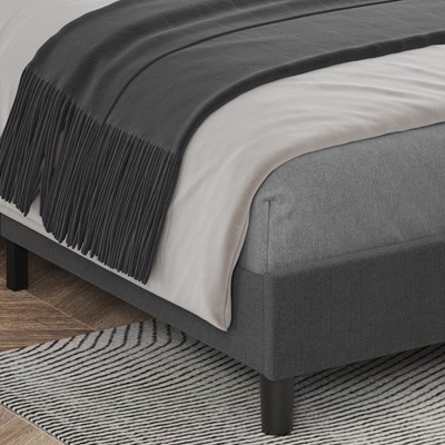 Close-up of the bed corner with gray fabric upholstery