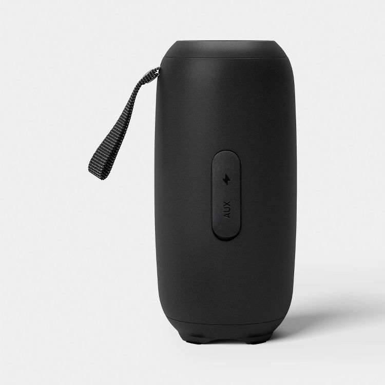 A black colored portable speaker with a strap and an AUX button on the side.