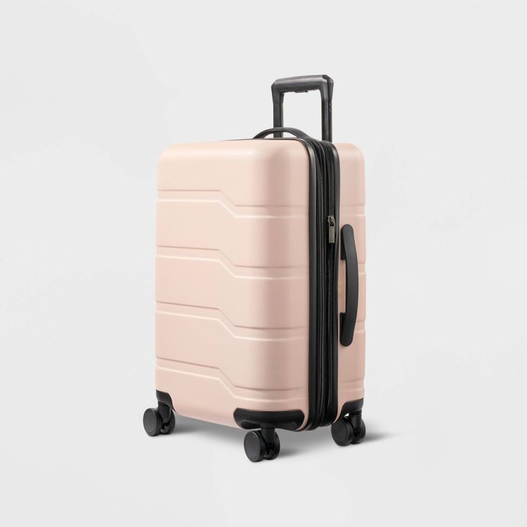 A pink colored hard-shell suitcase with four wheels and a telescopic handle.