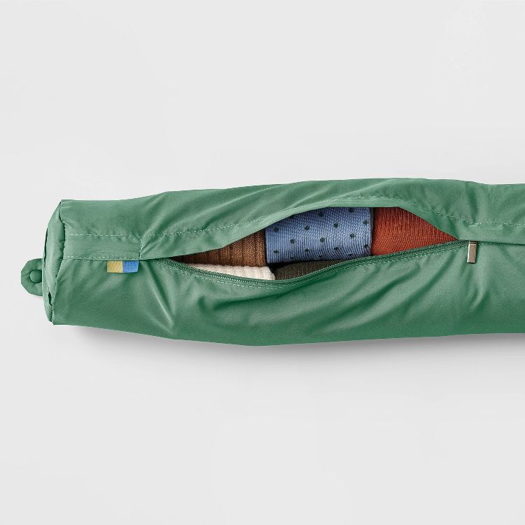 A green colored zippered bag partially open to reveal folded clothing inside.