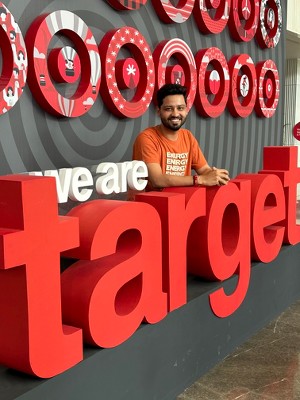 Aviral smiling and posing over We are target banner.