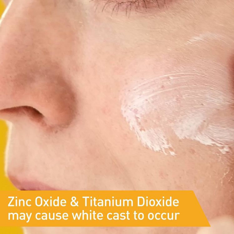 A close-up of a person's cheek with white colored sunscreen applied, accompanied by text stating "Zinc Oxide & Titanium Dioxide may cause white cast to occur."
