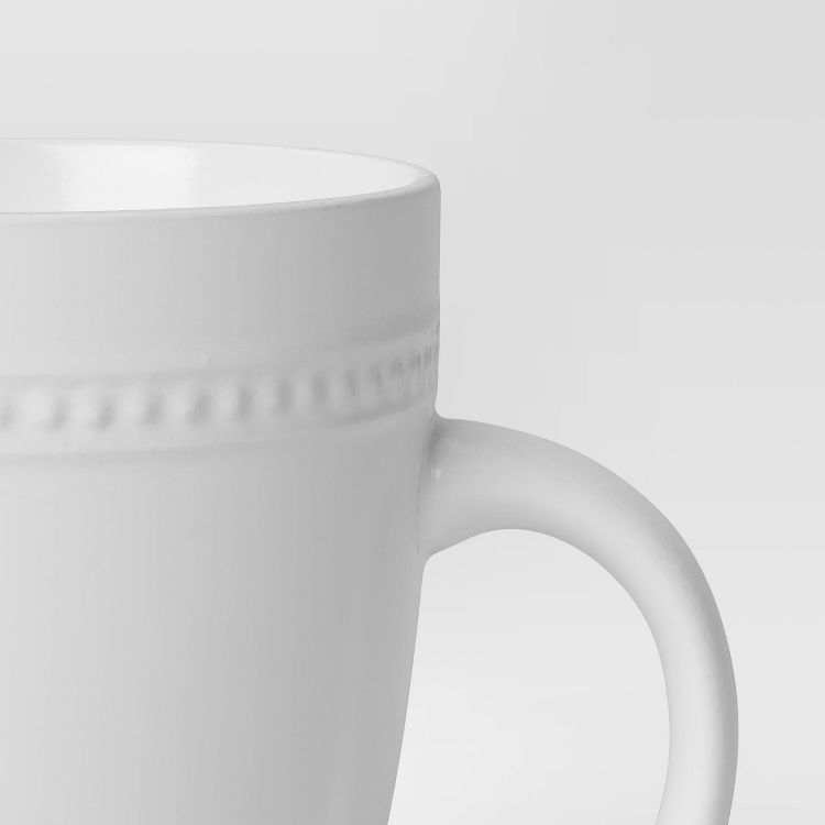 White colored mug with a textured band near the rim and a curved handle.