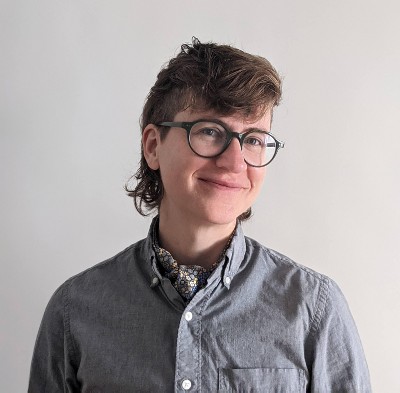 Target Principal Engineer Emi Lyman, photographed wearing glasses and a chambray button down shirt, smiling against a neutral background