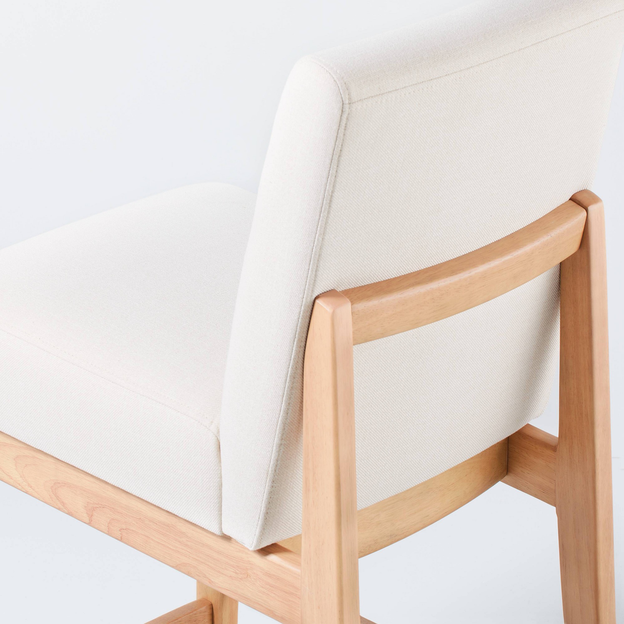 Close-up detail of the upholstery and wooden frame of a slipper counter stool.
