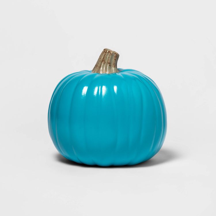 A shiny turquoise colored pumpkin with a brown stem on a plain background.
