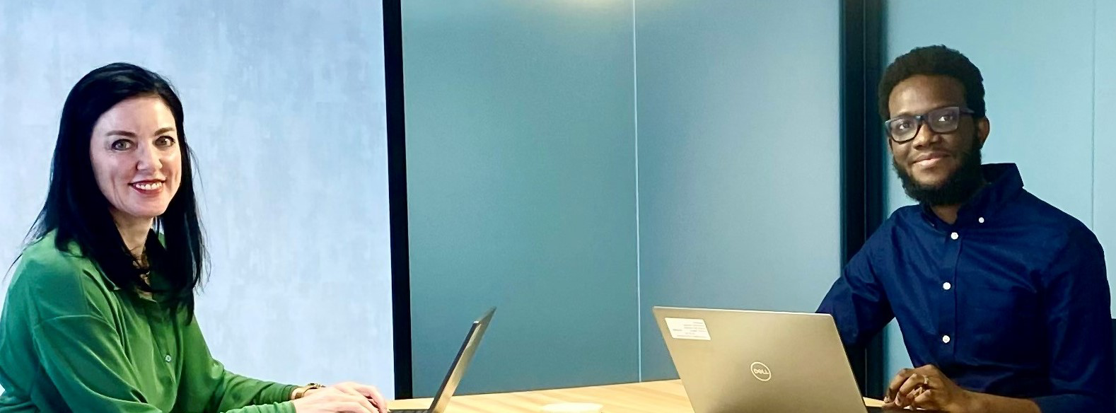 two Target team members seated in a conference room at Target HQ, with laptops open in front of them. Brenda is in a green shirt and seated on the left of the frame, and Nii is wearing a blue shirt, seated on the right side of the frame.