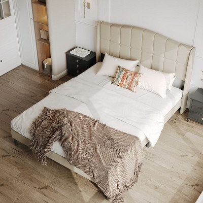 Beige upholstered bed with white linens and decorative pillows in a modern bedroom