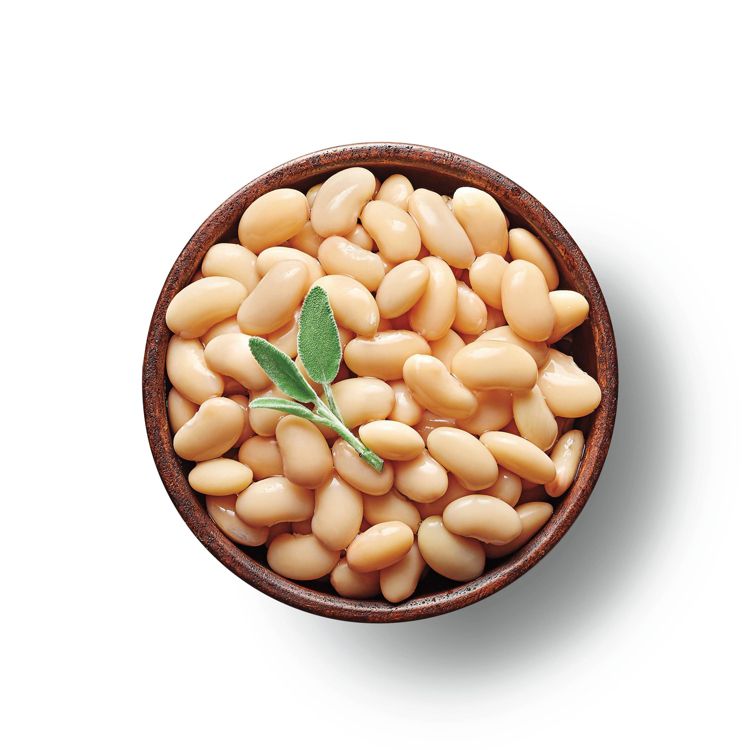 A bowl filled with light beige colored beans garnished with a sprig of green leaves.